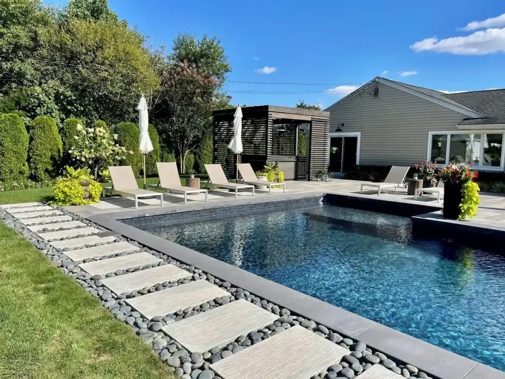 Modern backyard using contemporary landscaping materials like decorative concrete, modular planters, and stainless steel features.